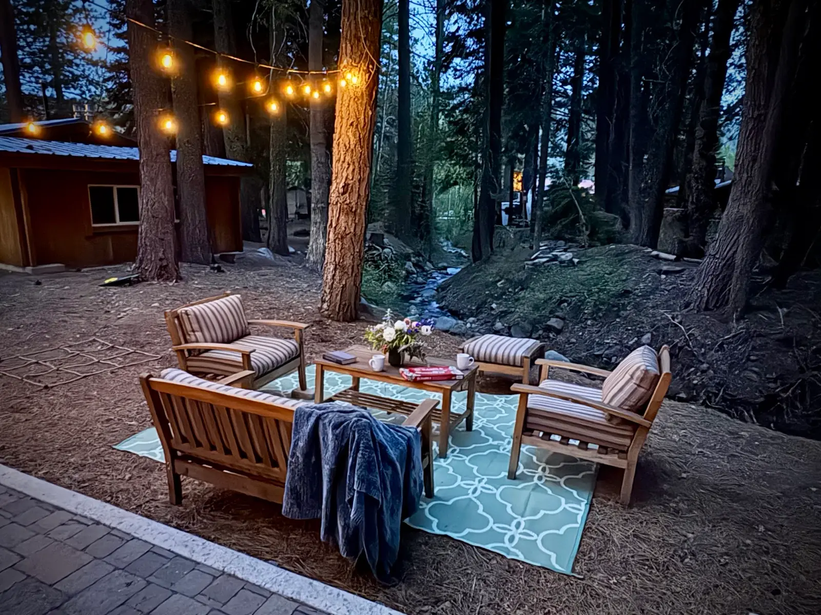 Creekside seating under string lights at dusk
